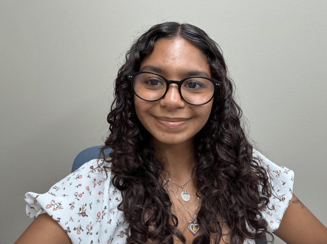Jazelyn, Kaplan Student Engagement Manager at UConn, alongside a University of Connecticut campus building.