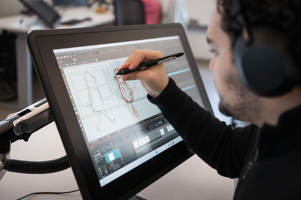 Student creating digital animation artwork on a drawing tablet in an animation studio at Emily Carr University.