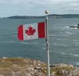 Canadian flag overlooking a rugged coastline and ocean view featured in the Explore Canada video
