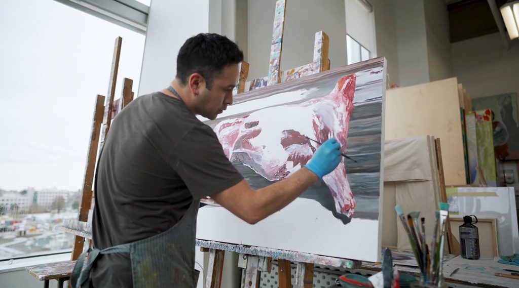 Student creating a painting in an art studio at ECU